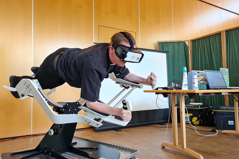 DRW-Vorstandsvorsitzender Martin Riß mit VR-Brille beim Testen des Ganzkörpertrainers „Icaros“. In der virtuellen Realität schwebte er wie ein Vogel durch ein Gebirgstal. 